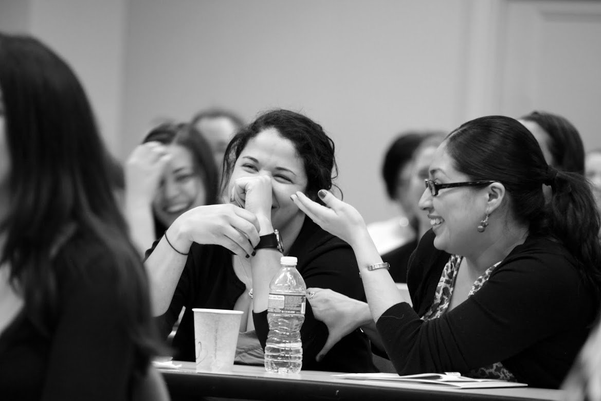 Two people at a workshop table laughing and engaging