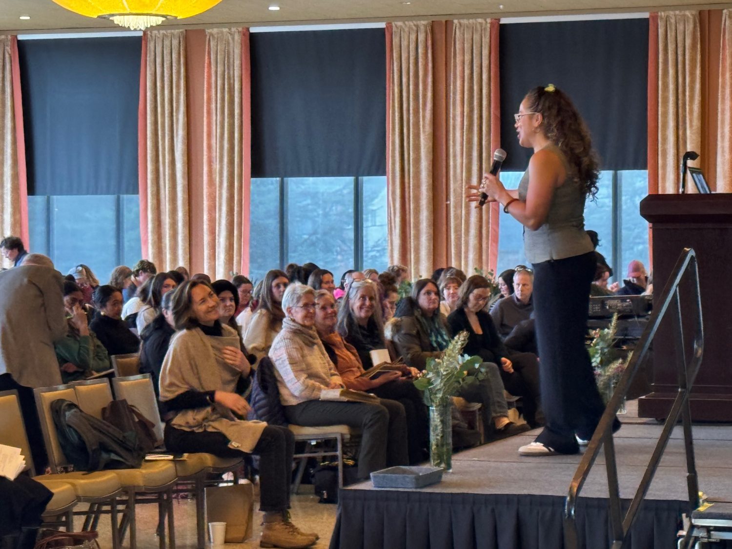 View from side of platform stage showing Laura speaking to engaged audience